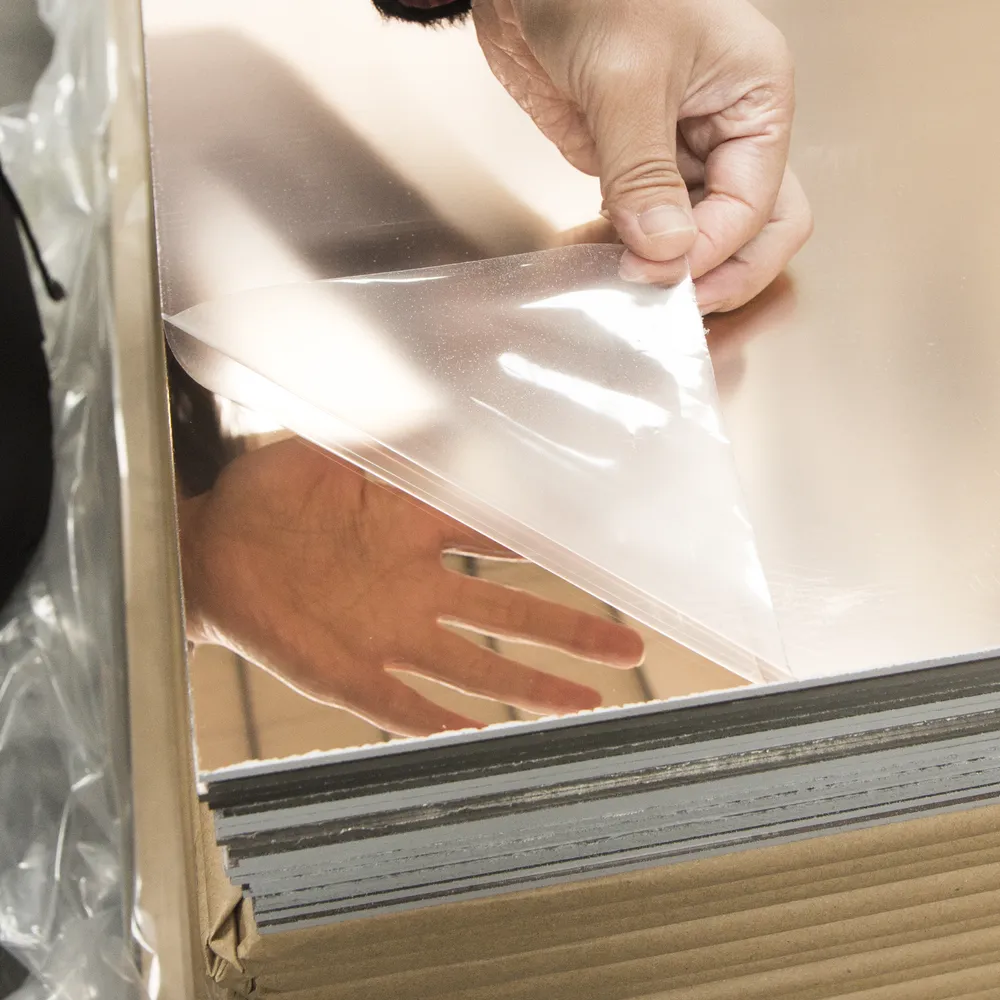 Hand peeling protective film from a large colored acrylic mirror sheet (2440×1220 mm)